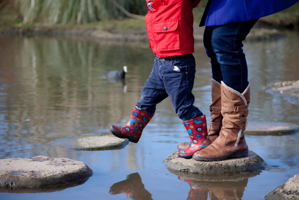 Parent helping child across stepping stones. Image to represent how coaching helps you find ways forward one step at a time.